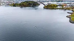 Outdoor Activity Prints: Aerial view of kayaks paddling in a calm bay with a bridge and cityscape in the background