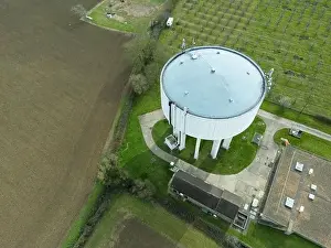 Water Tower Prints: Aerial view of a large concrete water tower seen next to a large shed which houses chickens