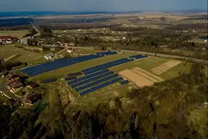 Aerial view of large field of solar photo voltaic panels system producing renewable clean energy on green grass