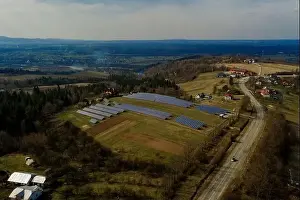 Aerial view of large field of solar photo voltaic panels system producing renewable clean energy on green grass
