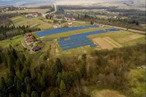 Aerial view of large field of solar photo voltaic panels system producing renewable clean energy on green grass