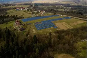 Aerial view of large field of solar photo voltaic panels system producing renewable clean energy on green grass