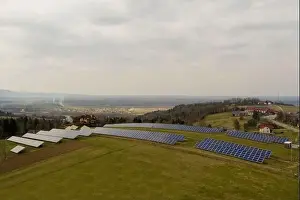 Aerial view of large field of solar photo voltaic panels system producing renewable clean energy on green grass