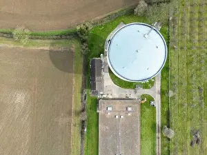 Water Tower Prints: Aerial, top down view of a large water tower seen at the edge of a large shed which houses chickens