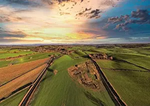 Farmyard Prints: Aerial view of a lush countryside at sunset with vibrant skies and patchwork fields