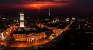 Aerial view on Lviv city hall at night from drone with lightning on the sky