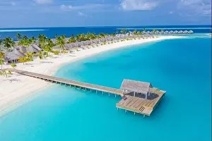 Aerial view of Maldives island, luxury water villas resort and wooden pier. Beautiful sky and ocean lagoon beach background. Summer vacation holiday