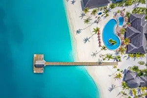 Aerial view of Maldives island, luxury water villas resort and wooden pier. Beautiful sky and ocean lagoon beach background. Summer vacation holiday