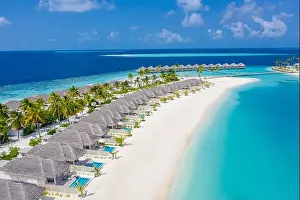 Aerial view of Maldives island, luxury water villas resort and wooden pier. Beautiful sky and ocean lagoon beach background. Summer vacation holiday