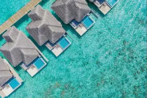 Aerial view of Maldives island, luxury water villas resort and wooden pier. Beautiful sky and ocean lagoon beach background. Summer vacation holiday