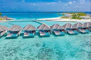 Aerial view of Maldives island, luxury water villas resort and wooden pier. Beautiful sky and ocean lagoon beach background. Summer vacation holiday