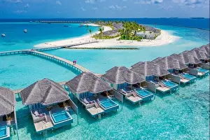 Aerial view of Maldives island, luxury water villas resort and wooden pier. Beautiful sky and ocean lagoon beach background. Summer vacation holiday