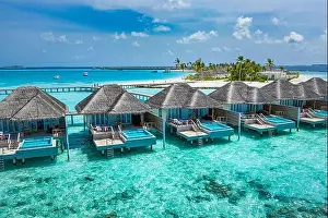 Aerial view of Maldives island, luxury water villas resort and wooden pier. Beautiful sky and ocean lagoon beach background. Summer vacation holiday
