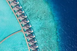 Aerial view of Maldives island, luxury water villas resort and wooden pier. Beautiful sky and ocean lagoon beach background. Summer vacation holiday