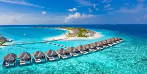 Aerial view of Maldives island, luxury water villas resort and wooden pier. Beautiful sky and ocean lagoon beach background. Summer vacation holiday