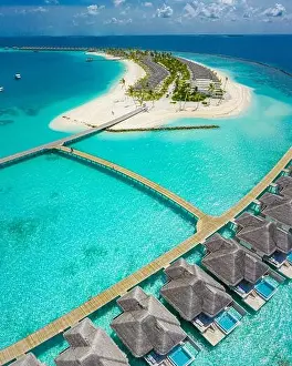 Aerial view of Maldives island, luxury water villas resort and wooden pier. Beautiful sky and ocean lagoon beach background. Summer vacation holiday
