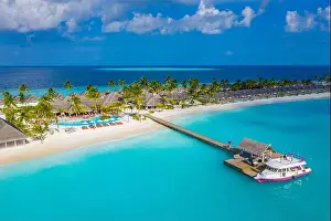 Aerial view of Maldives island, luxury water villas resort and wooden pier. Beautiful sky and ocean lagoon beach background. Summer vacation holiday