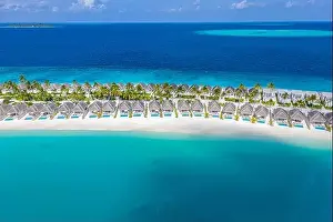 Aerial view of Maldives island, luxury water villas resort and wooden pier. Beautiful sky and ocean lagoon beach background. Summer vacation holiday