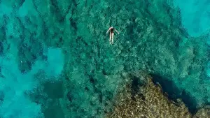 Crystal Water Prints: Aerial view of mediterranean sea bay with a girl swimming in the middle