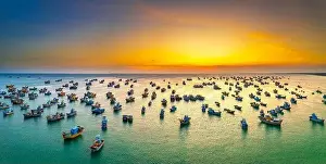 Aerial view of Mui Ne fishing village in sunset sky with hundreds of boats anchored to avoid storms