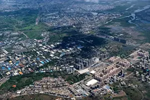 Urban Living Prints: An aerial view of Mumbai's skyline passing over a building with roads and bridges