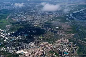Urban Living Prints: An aerial view of Mumbai's skyline passing over a building with roads and bridges