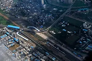 Urban Living Prints: An aerial view of Mumbai's skyline passing over a building with roads and bridges