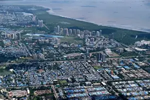 Urban Living Prints: An aerial view of Mumbai's skyline passing over a building with roads and bridges