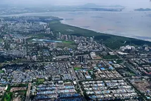 Urban Living Prints: An aerial view of Mumbai's skyline passing over a building with roads and bridges