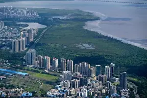 Urban Living Prints: An aerial view of Mumbai's skyline passing over a building with roads and bridges
