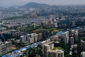 Urban Living Prints: An aerial view of Mumbai's skyline passing over a building with roads and bridges