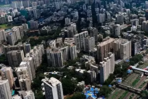 Urban Living Prints: An aerial view of Mumbai's skyline passing over a building with roads and bridges