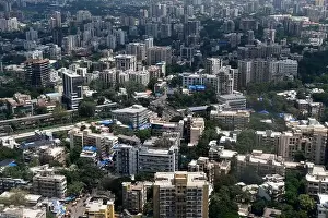 Urban Living Prints: An aerial view of Mumbai's skyline passing over a building with roads and bridges