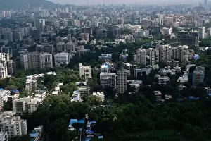 Urban Living Prints: An aerial view of Mumbai's skyline passing over a building with roads and bridges