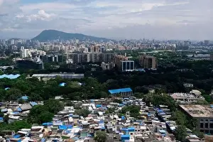 Urban Living Prints: An aerial view of Mumbai's skyline passing over a building with roads and bridges