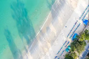 Aerial view of people swimming on the pink swim ring in the transparent turquoise sea in Phuket, Thailand
