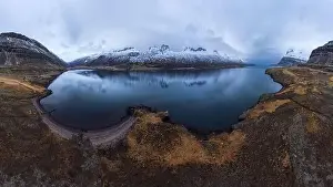 Aerial view of pond surrounded by snowy mountains located under cloudy sky in Iceland during daytime