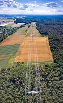Aerial view along a power line in forest area with metal power poles and high voltage wires in Germany