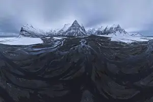 From above aerial view of river estuary covered with ice in snowy valley of mountains in winter time in Iceland