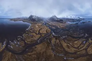 From above aerial view of river estuary and ocean coast near mountain peaks covered with snow in winter time in Iceland