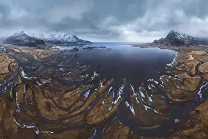 From above aerial view of river estuary and ocean coast near mountain peaks covered with snow in winter time in Iceland