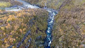 Aerial view of a river flowing through a rugged canyon surrounded by autumn foliage