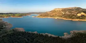 Vegetate Prints: Aerial view of river water flowing from Guadalhorce Dam of Gobantes Spain against rocky mountainous terrain under blue