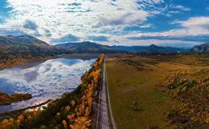 Aerial view of road and lake in beautiful autumn Altai forest