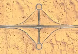 Sharjah Prints: Aerial view of a road and roundabout crossing in the middle of a sandy desert in afternoon light