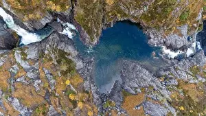 Directly Above Prints: Aerial view of a rocky landscape with a small waterfall flowing into a clear blue pool surrounded by autumn foliage