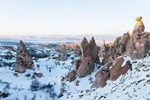 Cappadocia Prints: Aerial view of rough rock formations covered with white snow against cloudless evening sky in Cappadocia