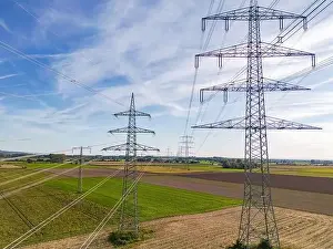 Rural Area Prints: Aerial view of a row of high voltage pylons with many power lines in rural area to the horizon
