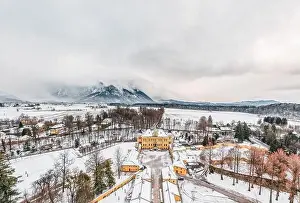 Snow Mountain Prints: Aerial view of Schloss Hellbrunn covered in snow with view of Untersberg near Salzburg Outskirts in winter time