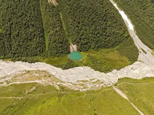 Channels Prints: Aerial view shows a small turquoise glacial pond by an alpine forest in Svaneti